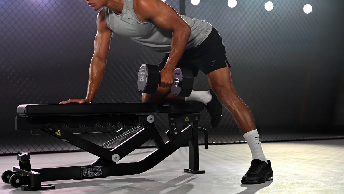 Atleta realizando un remo con una mancuerna apoyado en un banco Hammer Strength